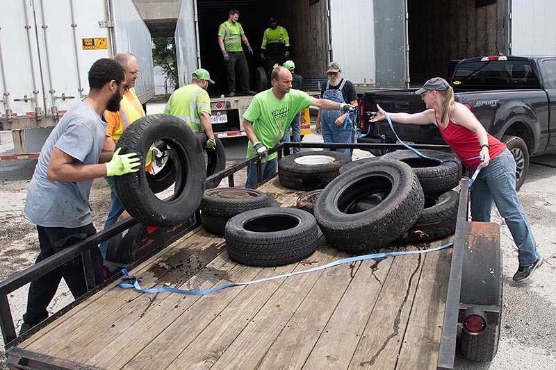 several people unloading ten old tires from a flatbed trailer