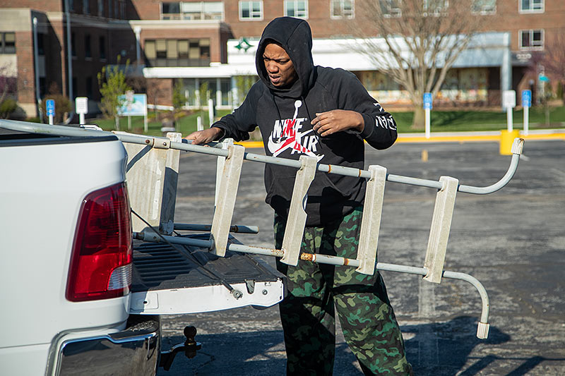 man removing old ladder from pickup truck