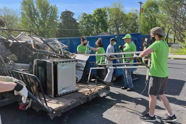 team of five people helping unload junk from a trailer